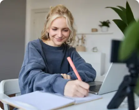 TMS Vertiefung –zufriedene junge Frau sitzt vor ihrem Laptop und schreibt Notizen