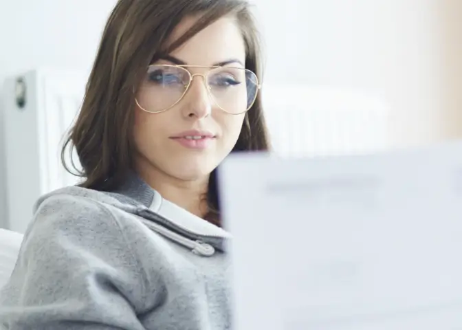 Junge Frau mit Brille begutachtet ihr Motivationsschreiben und Lebenslauf