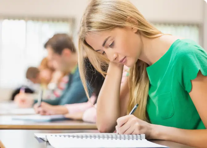 TMS Generalprobe –junge Frau schreibt einen Test. Im Hintergrund sind noch weitere angehende Studenten.