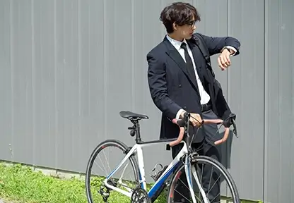 Blog planZ – junger Mann mit Anzug und Fahrrad schaut auf seine Uhr