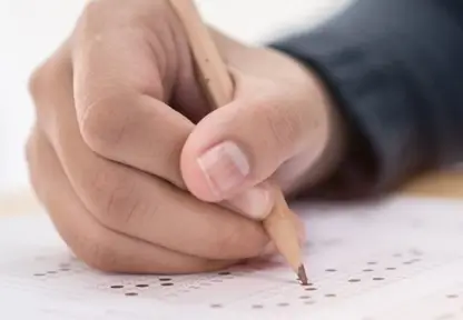 Eine Hand hält Stift in der Hand und kreuzt Multiple Choice Fragen an