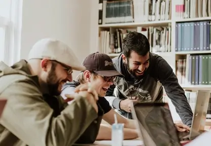 Drei Studenden schauen gemeinsam auf einen Computer