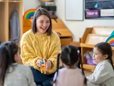 Junge Studentin spielt mit Kindern im Kindergarten